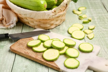 Tahta ve hasır sepette yeşil ahşap arka planda taze kabak.