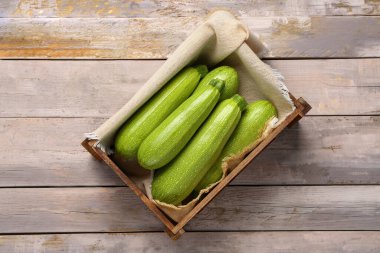 Gri ahşap arka planda yeşil kabaklı bir kutu.