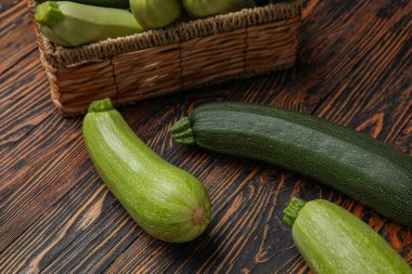 Ahşap zemin üzerinde taze yeşil kabak olan hasır kutu.