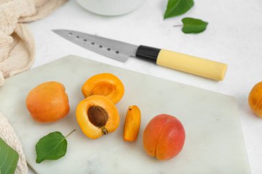 Taze kayısıları ve beyaz arkaplanda yaprakları olan tahta