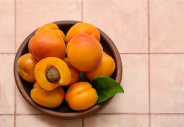 Taze kayısılı kase ve pembe fayanslı yaprak.