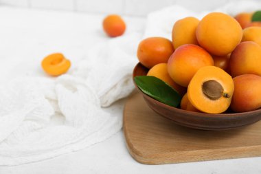 Beyaz masada bir kase taze kayısı var.