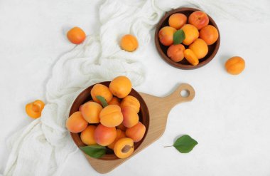 Beyaz masada taze kayısılar ve tabaklar.