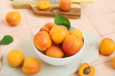 Pembe fayansların üzerinde taze kayısılar olan tahtalar ve kaseler.