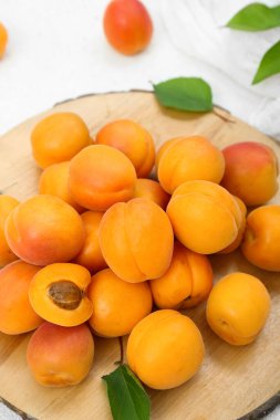 Taze kayısıları ve beyaz arkaplanda yaprakları olan tahta