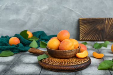 Taze kayısılar ve gri fayansların üzerinde yapraklar.