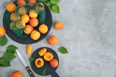 Gri masadaki kayısılarla dolu tahtalar ve ip torbaları.