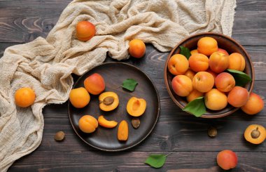 Tabak ve tabak taze kayısılarla ahşap masada.