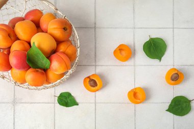 Beyaz fayans masasında taze kayısı sepeti.