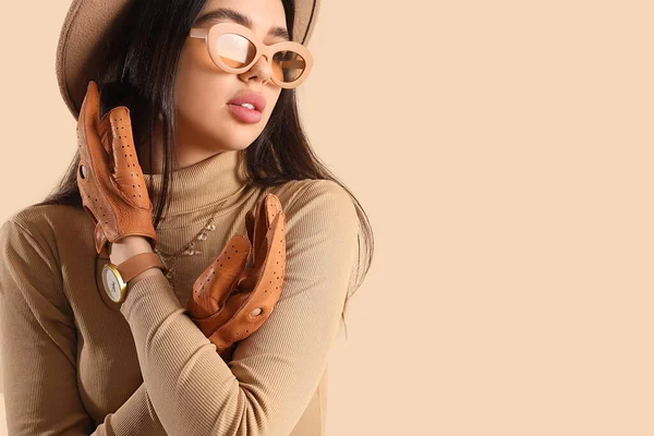 スタイリッシュな若い女性でサングラスと革の手袋でベージュの背景 — ストック写真