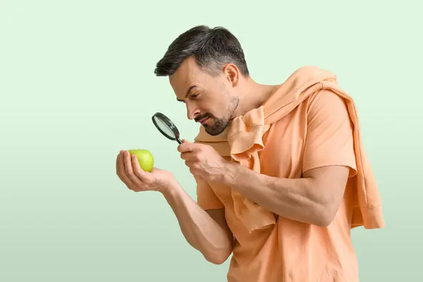 Knappe Man Met Vergrootglas Appel Groene Achtergrond — Stockfoto