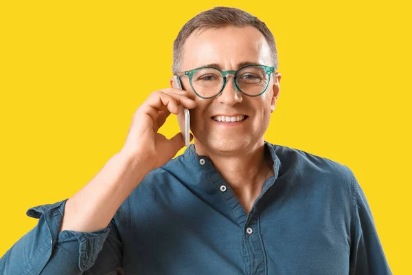Dojrzały Mężczyzna Okularach Rozmawia Przez Telefon Komórkowy Żółtym Tle — Zdjęcie stockowe