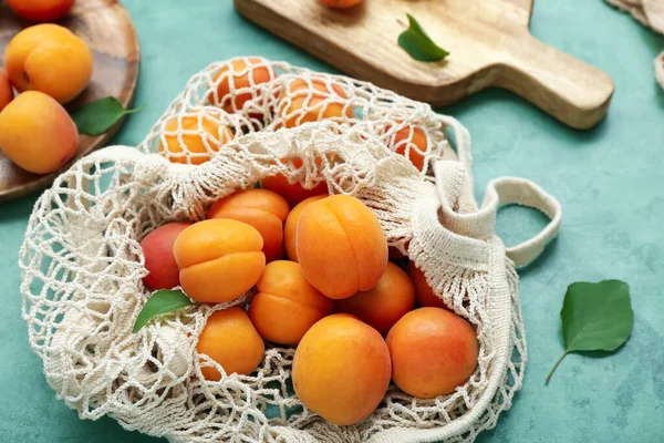 stock image String bag with fresh apricots on green background