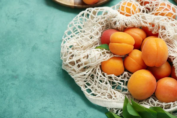 stock image String bag with fresh apricots on green background