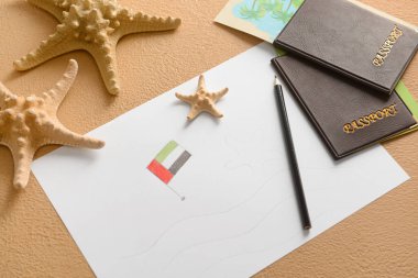 Bej arka planda Birleşik Arap Emirlikleri bayrağı, deniz yıldızları ve pasaportları olan kağıt kağıtlar.