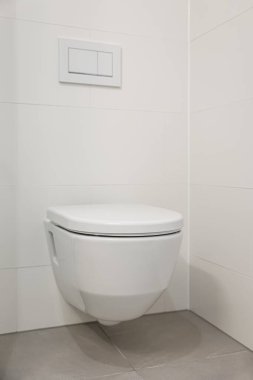 Beyaz klozet, ışık duvarının yanında.
