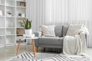 Aydınlık oturma odasındaki yastıklı rahat bir kanepe.