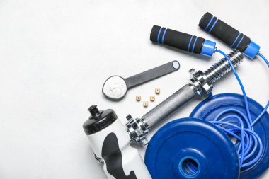 Amino asit takviyeli kepçe, hafif arka planda bir şişe su ve spor ekipmanı.