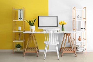 Modern bilgisayar, güzel narsisli çiçekler ve kahve ile şık bir ofis.