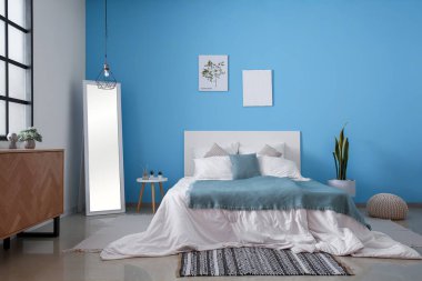 Yatak odasının içi rahat yatak odası, ayna ve ahşap dolap.