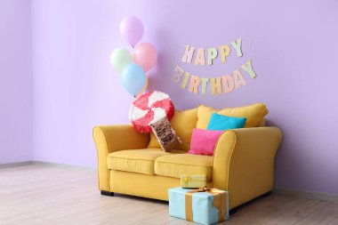 Doğum günü için dekore edilmiş oturma odasının içinde balonlar, pinyatalar ve çelenkler var.