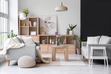 Gri kanepeleri ve büyük pencereleri olan aydınlık oturma odasının içinde.