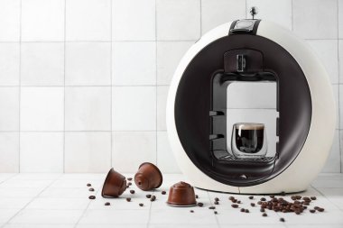 Modern kapsül kahve makinesi beyaz masada bir fincan espresso, kapsül ve fasulye.