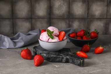 Bir kase lezzetli dondurma, taze çilek ve grunge masasında nane şekeri.