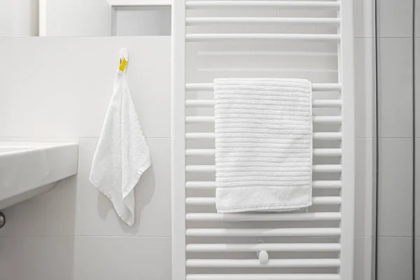 stock image Heated towel rail near light wall in bathroom