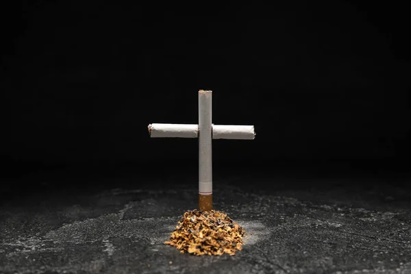 stock image Tobacco grave with cigarette cross on dark background. Stop smoking concept