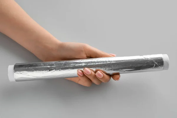 Vrouwelijke Hand Met Aluminiumfolie Rol Grijze Achtergrond Close — Stockfoto