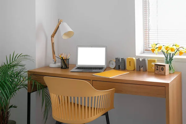 Комфортное Рабочее Место Современным Ноутбуком Цветами Нарцисса Столе Комнате — стоковое фото
