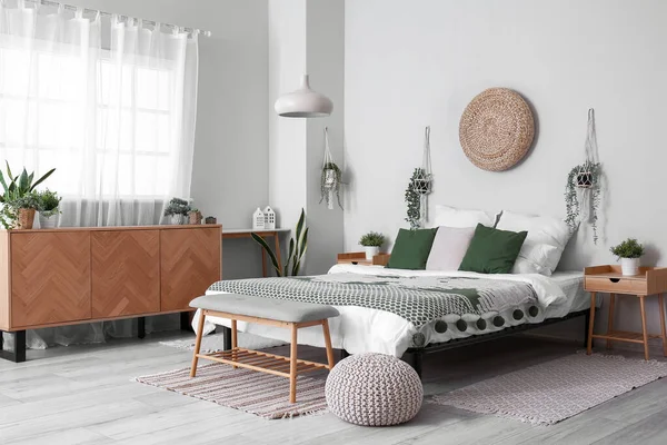 居心地の良いベッド 木製のキャビネットと吊り観葉植物と光の寝室のインテリア — ストック写真