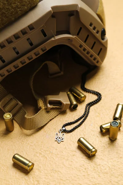 Askeri miğfer, kurşun ve zincir Ukrayna arması bej arka planda, yakın plan.