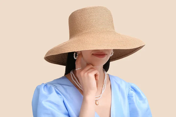 stock image Beautiful young woman wearing stylish jewelry and wicker hat near beige wall