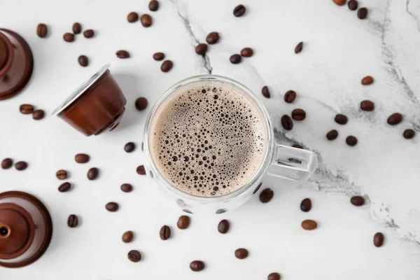 白いテーブルの上においしいコーヒー ポッド 豆のカップ — ストック写真