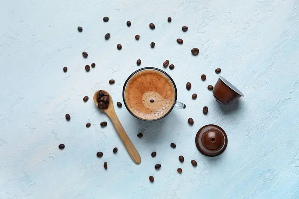 青いテーブルの上においしいコーヒー 木製のスプーン 豆とカプセルのカップ — ストック写真