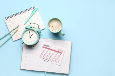 Takvim, alarm saati, kahve fincanı ve mavi arkaplanda not defteri olan kompozisyon