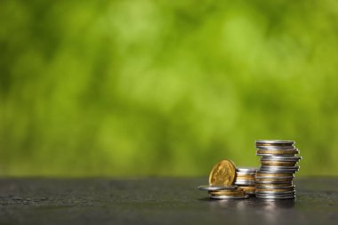 Masadaki bozuk para yığınları bulanık yeşil doğa arka planına karşı