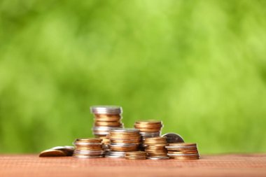 Masadaki bozuk para yığınları bulanık yeşil doğa arka planına karşı