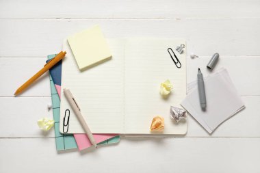 Beyaz ahşap zemin üzerine farklı kırtasiye malzemesi içeren yapışkan notlar.