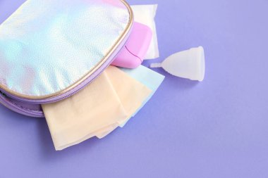 Kadının tampon kutulu kozmetik çantası, menekşe arkaplan pedleri.