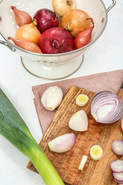 Tahta ve kevgir. Beyaz arka planda farklı soğan çeşitleri var.