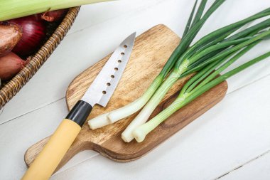 Tahta ve hasır sepette beyaz ahşap arka planda farklı türde soğan var.