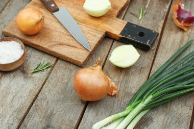 Kahverengi ahşap arka planda farklı soğan çeşitleri olan tahta