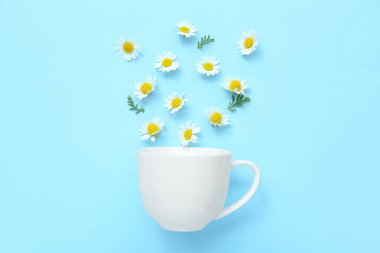 Mavi arka planda papatya çiçekli fincan