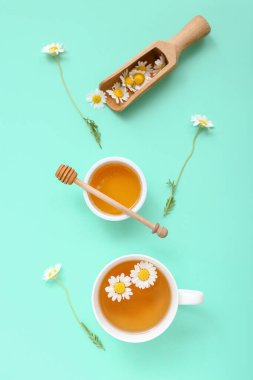 Ballı bir fincan sıcak çay ve turkuaz arka planda kepçe.