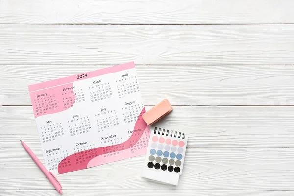 白色木制背景的日历 订书机和彩色调色板 — 图库照片