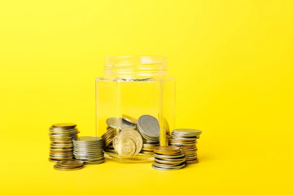 黄色の背景にコインを持つジャー 貯蓄概念 — ストック写真