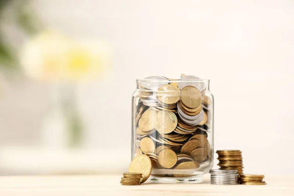 背景がぼやけて木製のテーブルの上にコインを持つジャー 貯蓄概念 — ストック写真